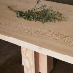 Cropped photo of the Soma Dining Table with decorative eucalyptus.