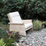 Pesuta chair made from Accoya with white cushions in a garden space.