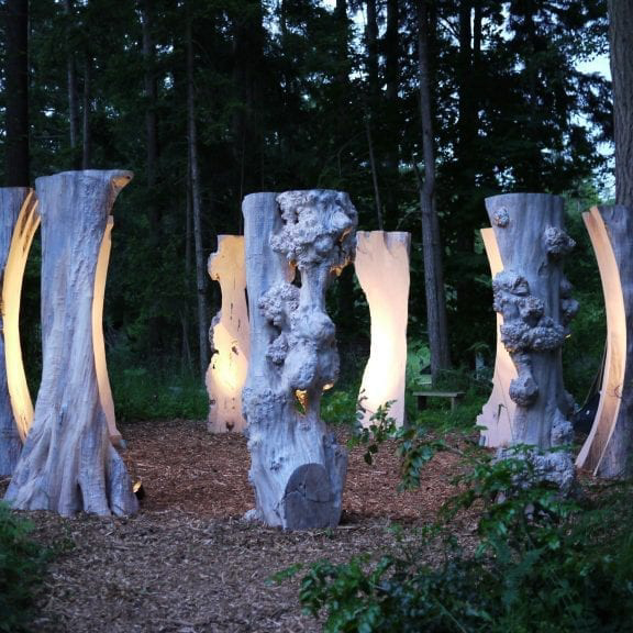 Nine Sentinel sculptures are pictured installed in a circular formation at the Van Dusen Botanical Gardens.