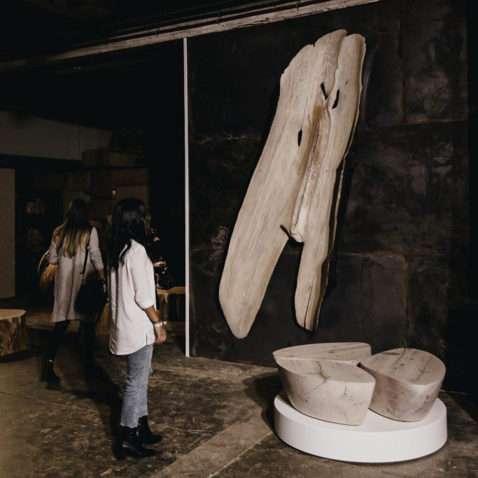 The shell sculpture displayed on a metal wall being viewed by two people.