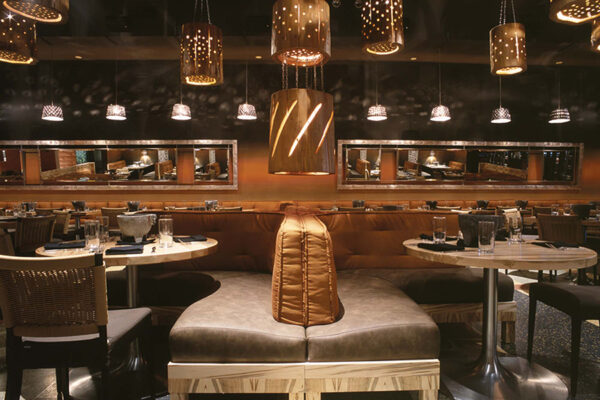 Illuminated log sculptures suspended above booths.