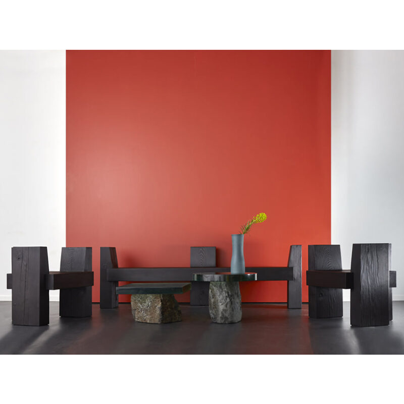 The beton brut bench chairs are pictured against a red background. They are surrounding two flow side tables.
