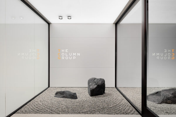 The entrance of the office with "The Colum Group" logo centered on the wall and two rocks directly below. One to rock to the right behind glass panels.