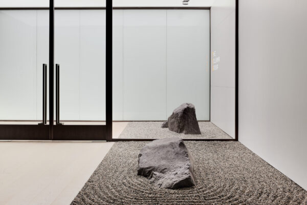 Two sloping rocks with raked gravel surrounding them located at the entrance of the office space.